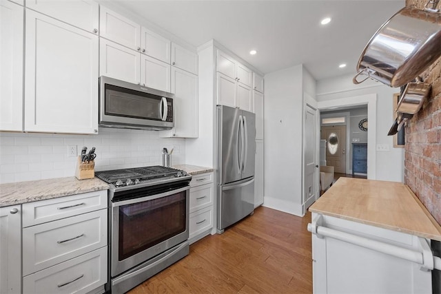 kitchen featuring white cabinets, appliances with stainless steel finishes, light wood-style floors, recessed lighting, and backsplash