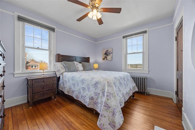 bedroom with a ceiling fan, baseboards, hardwood / wood-style floors, and radiator