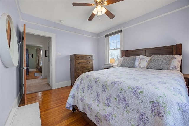 bedroom with ceiling fan, baseboards, and wood finished floors