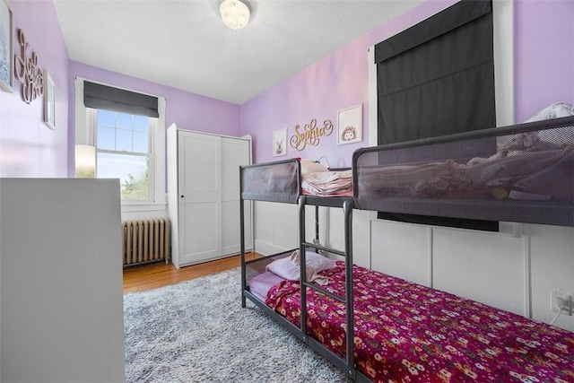 bedroom with radiator and wood finished floors