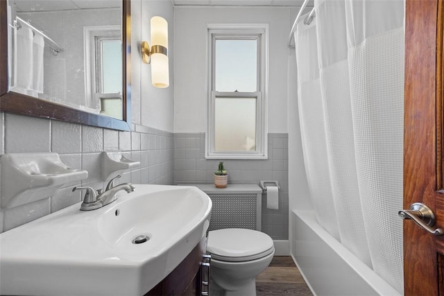 full bathroom with a wainscoted wall, toilet, wood finished floors, tile walls, and shower / tub combo