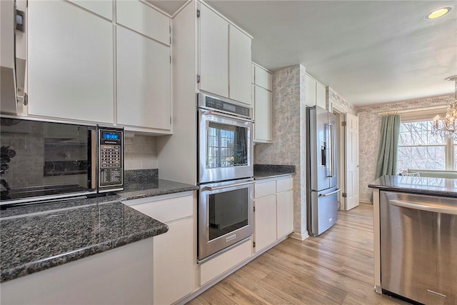 552 N Maple Ave, City Of Greensburg, PA 15601 - kitchen featuring dark stone countertops, white cabinets, an inviting chandelier, stainless steel appliances, and light wood-style flooring