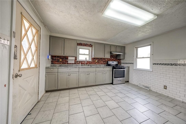 627 Rostraver Rd, Belle Vernon, PA 15012 - kitchen with gray cabinetry, gas range, under cabinet range hood, visible vents, and a sink