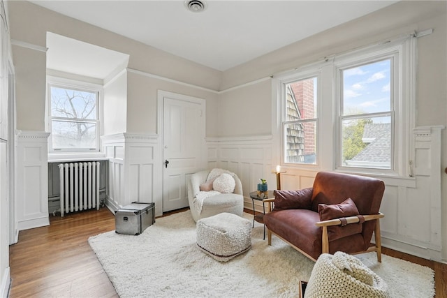 sitting room featuring visible vents, a wainscoted wall, radiator, and wood finished floors