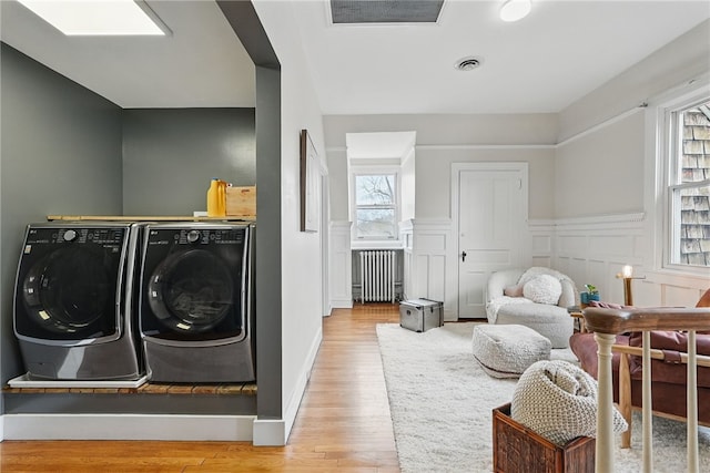 laundry area featuring visible vents, laundry area, radiator, wood finished floors, and washing machine and clothes dryer
