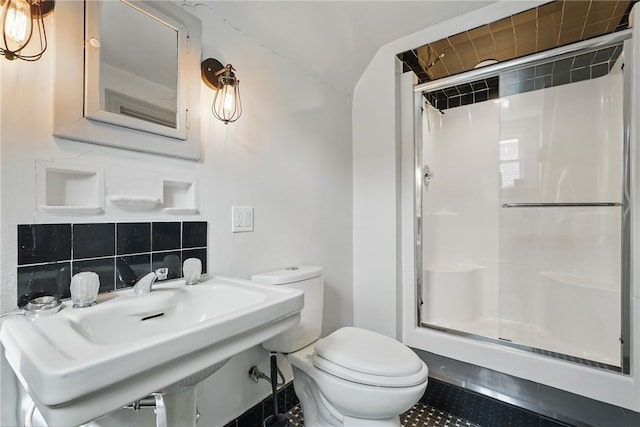 bathroom with toilet, a sink, backsplash, and a stall shower