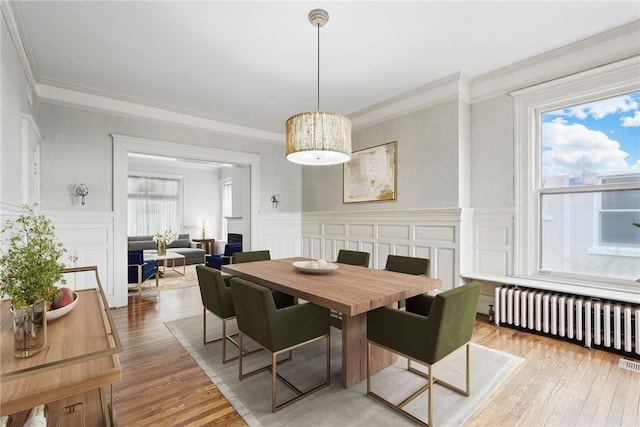 dining space featuring crown molding, wood finished floors, and radiator heating unit