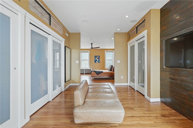 corridor featuring baseboards, light wood finished floors, radiator, recessed lighting, and french doors