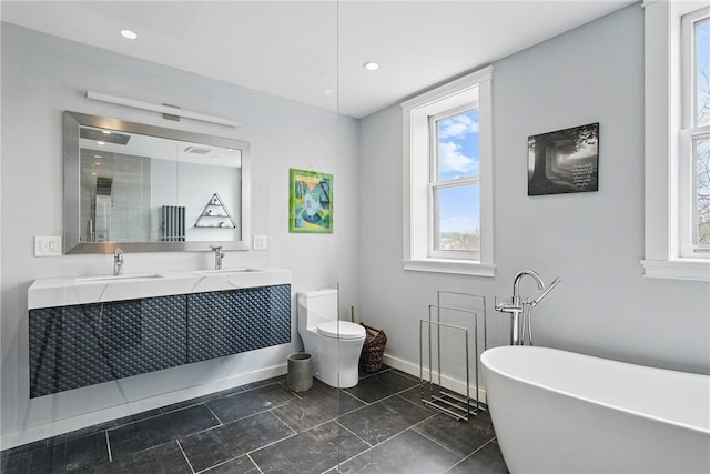 full bath featuring toilet, a soaking tub, double vanity, and a sink