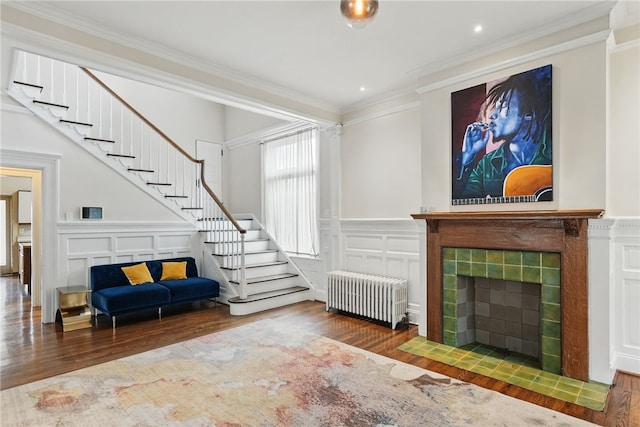 living area with stairs, a tile fireplace, radiator, and a decorative wall
