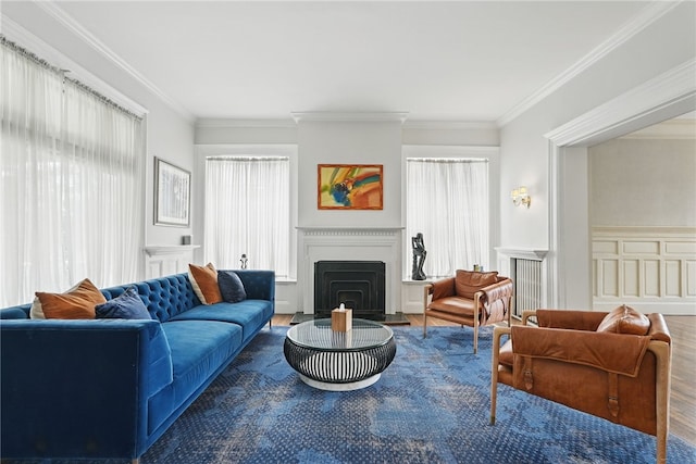 living room with a fireplace with flush hearth, wood finished floors, ornamental molding, and a wainscoted wall