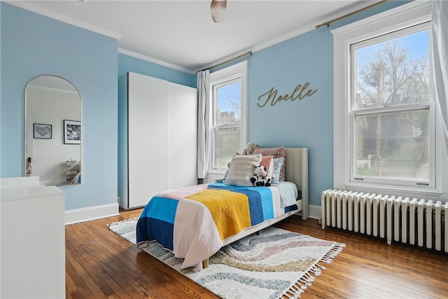 bedroom featuring radiator heating unit, wood-type flooring, baseboards, and ornamental molding