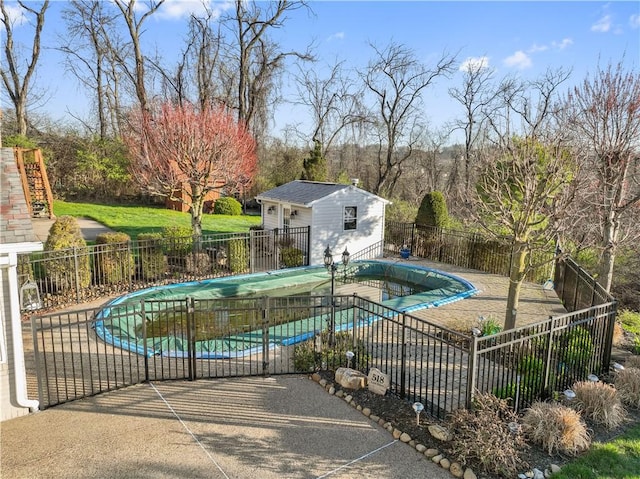 view of swimming pool featuring an exterior structure, a patio area, fence, an outbuilding, and a fenced in pool