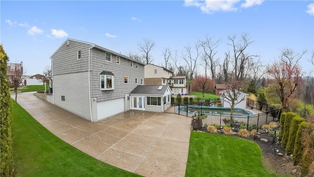 rear view of house featuring a fenced in pool, a patio, a garage, fence, and a lawn