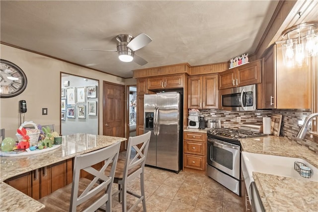 kitchen with a sink, brown cabinetry, appliances with stainless steel finishes, and ceiling fan