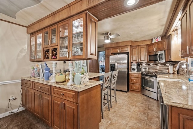 kitchen featuring stainless steel appliances, light stone countertops, and brown cabinets