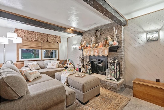 carpeted living area featuring wood walls, a stone fireplace, and beam ceiling