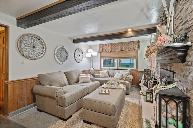 living room with wood walls, a fireplace, wainscoting, and beam ceiling