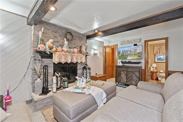 living area with wooden walls, beam ceiling, and a fireplace