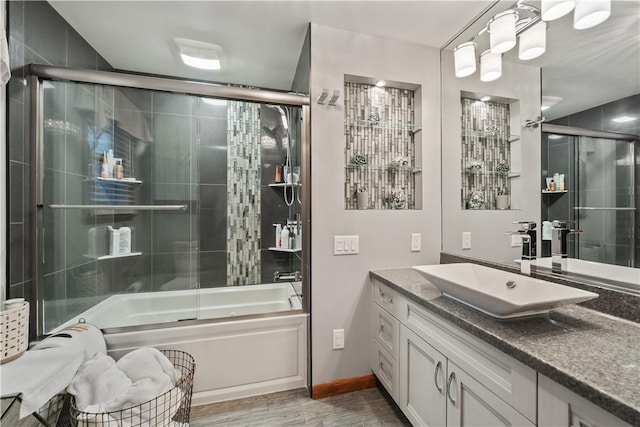 bathroom featuring baseboards, combined bath / shower with glass door, wood finished floors, and vanity