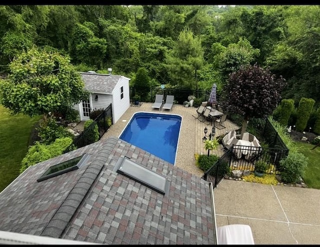 view of swimming pool featuring an outbuilding, a storage structure, a fenced backyard, a patio, and a fenced in pool