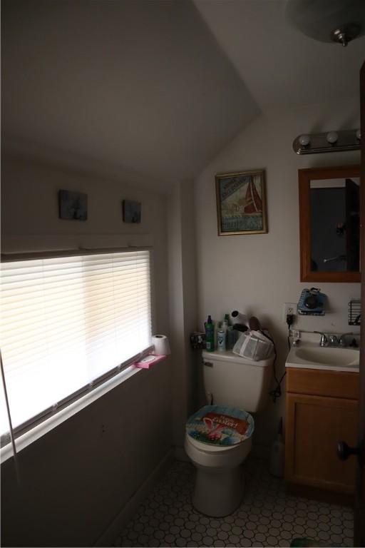 bathroom with toilet, vanity, tile patterned flooring, and lofted ceiling