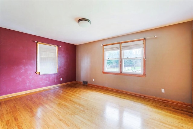 spare room featuring wood finished floors, baseboards, and visible vents