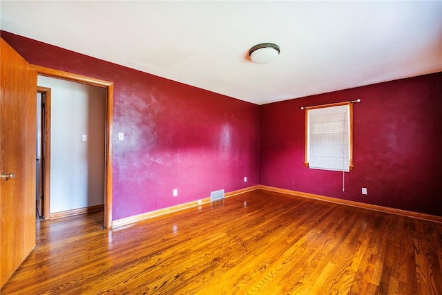 spare room with visible vents, baseboards, and wood finished floors