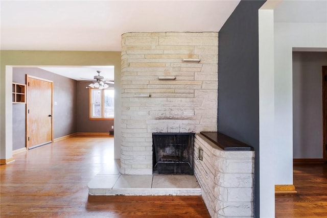 unfurnished living room with baseboards, a ceiling fan, wood finished floors, and a fireplace