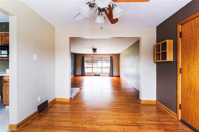 hall with visible vents, baseboards, and light wood finished floors