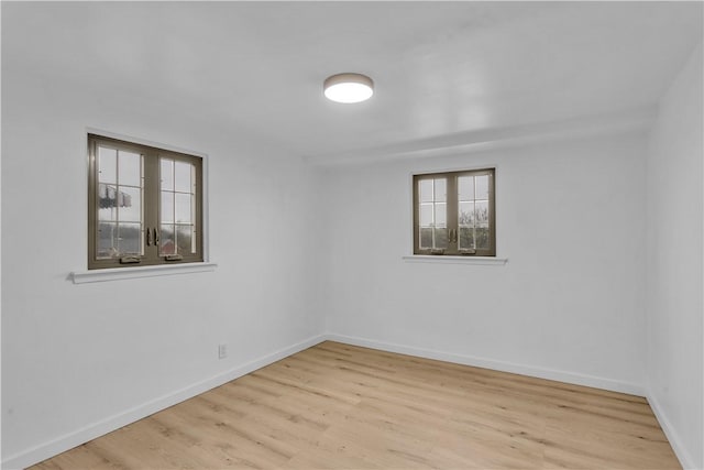spare room with baseboards, plenty of natural light, and wood finished floors