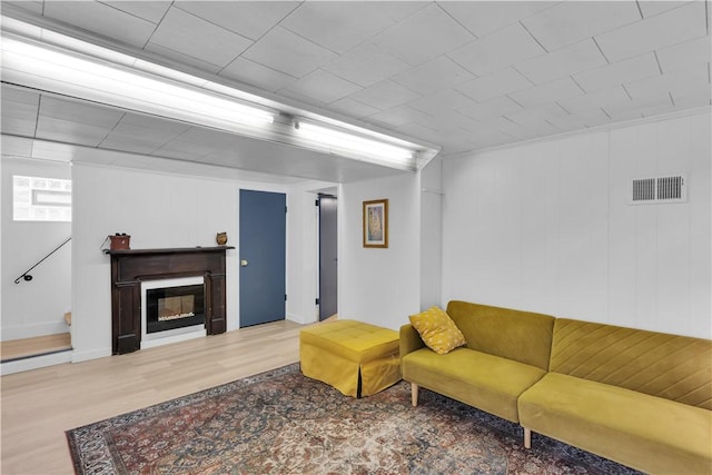 living room featuring a glass covered fireplace, visible vents, and wood finished floors