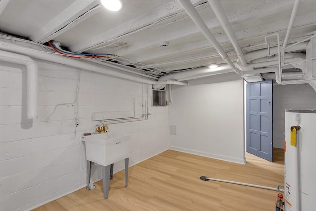 unfinished below grade area with light wood-style floors, concrete block wall, and water heater
