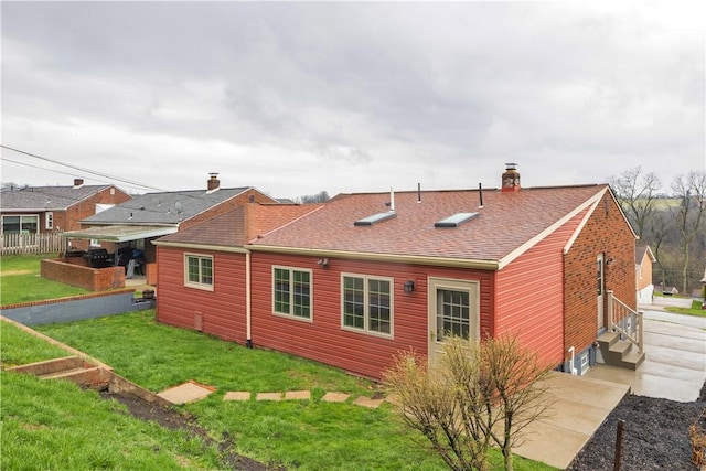 back of house with a yard, roof with shingles, fence, and a chimney