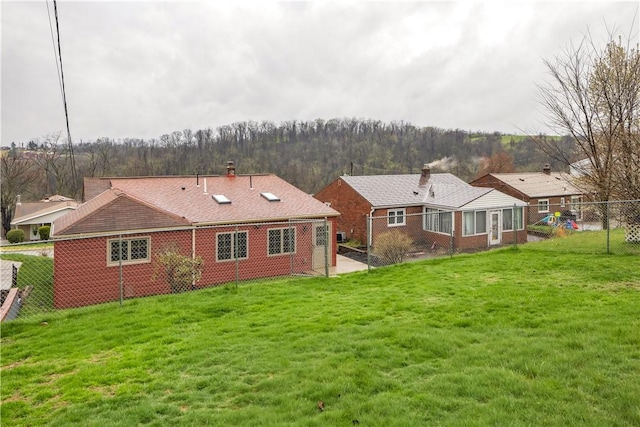 back of property with a yard, fence, and brick siding