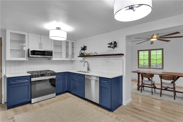 kitchen featuring a sink, light countertops, appliances with stainless steel finishes, light wood finished floors, and blue cabinets
