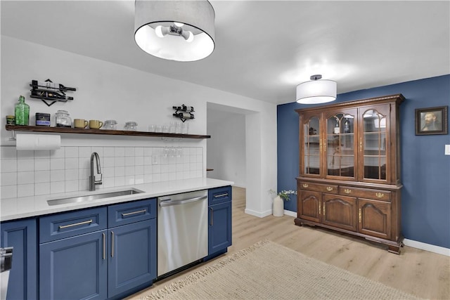kitchen featuring blue cabinetry, open shelves, stainless steel dishwasher, light wood finished floors, and a sink