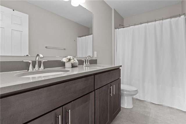 bathroom with toilet, double vanity, a sink, and tile patterned flooring
