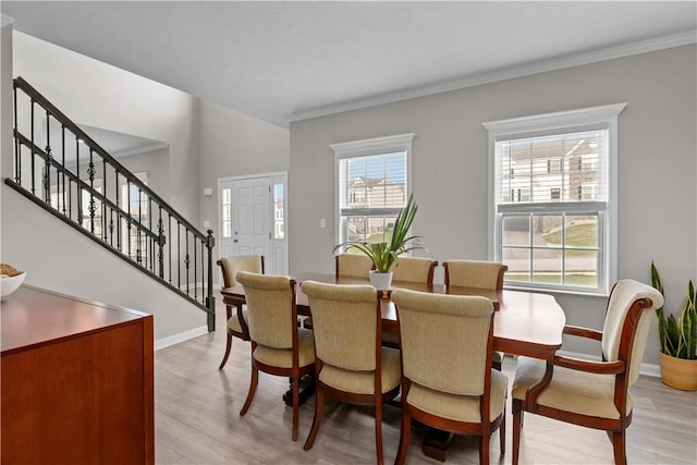dining room with stairs, light wood-style floors, baseboards, and ornamental molding