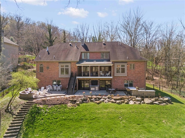 back of property featuring brick siding, a fire pit, a patio, and stairs