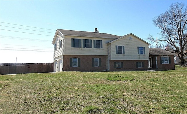 view of front facade with a garage, fence, a front lawn, and brick siding