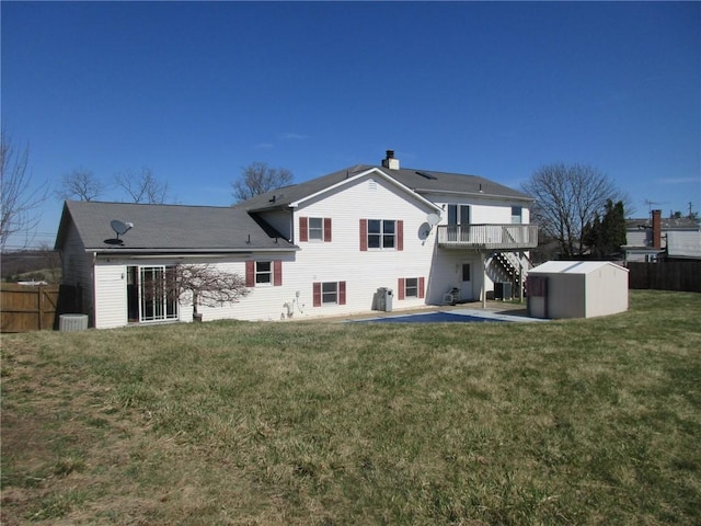 rear view of property with a lawn, fence, an outdoor structure, a patio, and a storage unit