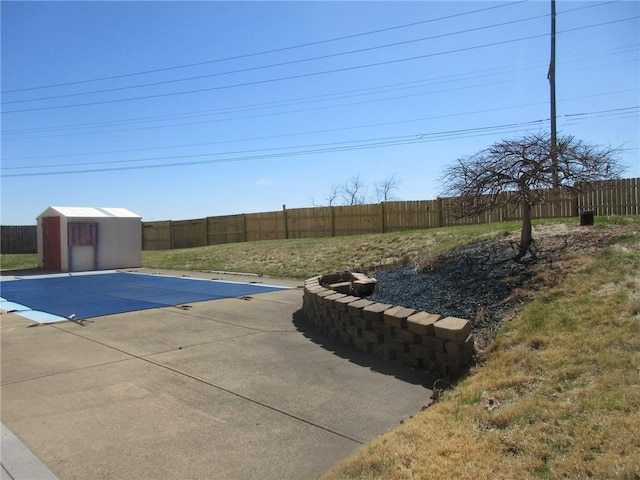 view of pool with an outbuilding, a fenced backyard, a patio, and a storage unit