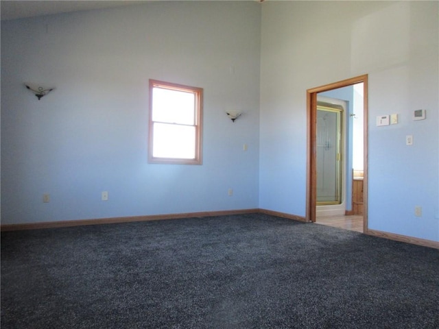 empty room with baseboards, high vaulted ceiling, and carpet