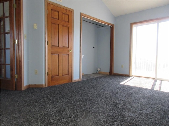 unfurnished bedroom featuring a closet, multiple windows, carpet, and lofted ceiling