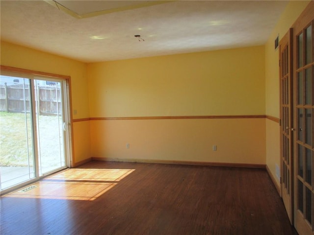 unfurnished room with wood finished floors, baseboards, and visible vents