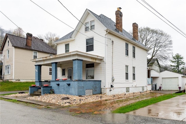 view of front facade featuring an outdoor structure, a chimney, a detached garage, driveway, and covered porch