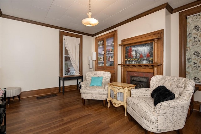 living area with crown molding, wood finished floors, and visible vents