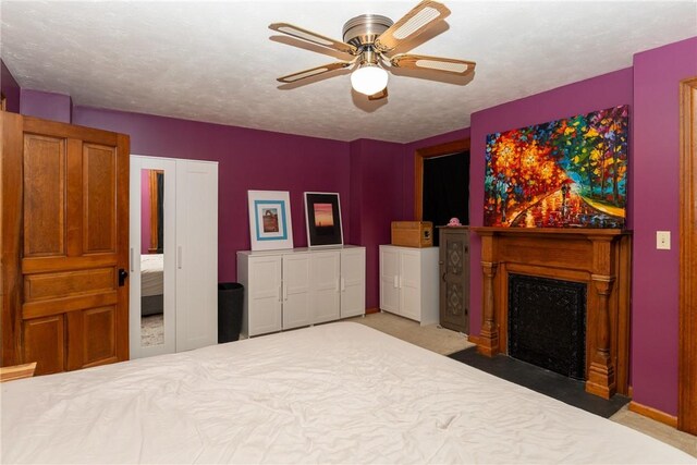 carpeted bedroom featuring a fireplace with flush hearth, ceiling fan, and baseboards