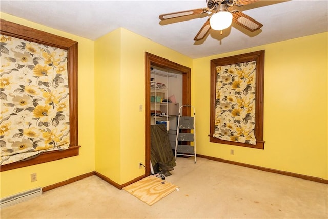 carpeted empty room featuring a baseboard heating unit, baseboards, and a ceiling fan